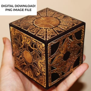 Może przedstawiać: Czarna kostka z ozdobnym, złotym wzorem. Kostka ma okrągły wzór na górze i bokach.