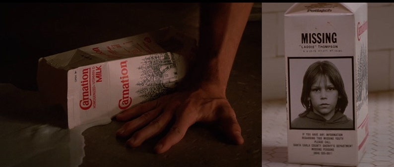 May include: A white carton of Carnation milk is lying on the floor, spilled and partially open. The carton is next to a white milk carton with a missing child poster on it. The poster features a photo of a young boy with brown hair and a black hooded sweatshirt. The poster reads "MISSING" and "LADDIE THOMPSON".