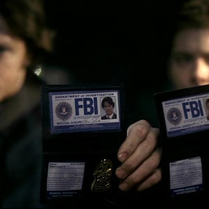 May include: Two men are holding up FBI badges. The badges are black with a blue and white design. The text on the badges reads "Department of Investigation FBI Special Agent".