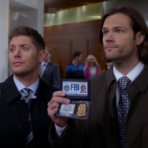 May include: Two men in suits and ties are holding up FBI badges. The badges are black with the letters FBI in white and a gold star in the centre.