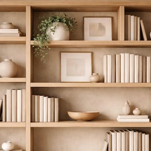 May include: A wooden bookshelf filled with decorative items. The shelves display stacks of books, vases, framed art, and plants. The color palette is neutral, with beige and cream tones, creating a calming aesthetic.