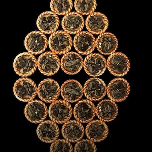 May include: A diamond-shaped arrangement of small, individual pies with a dark filling. The pies have a golden brown crust and are arranged in a symmetrical pattern.