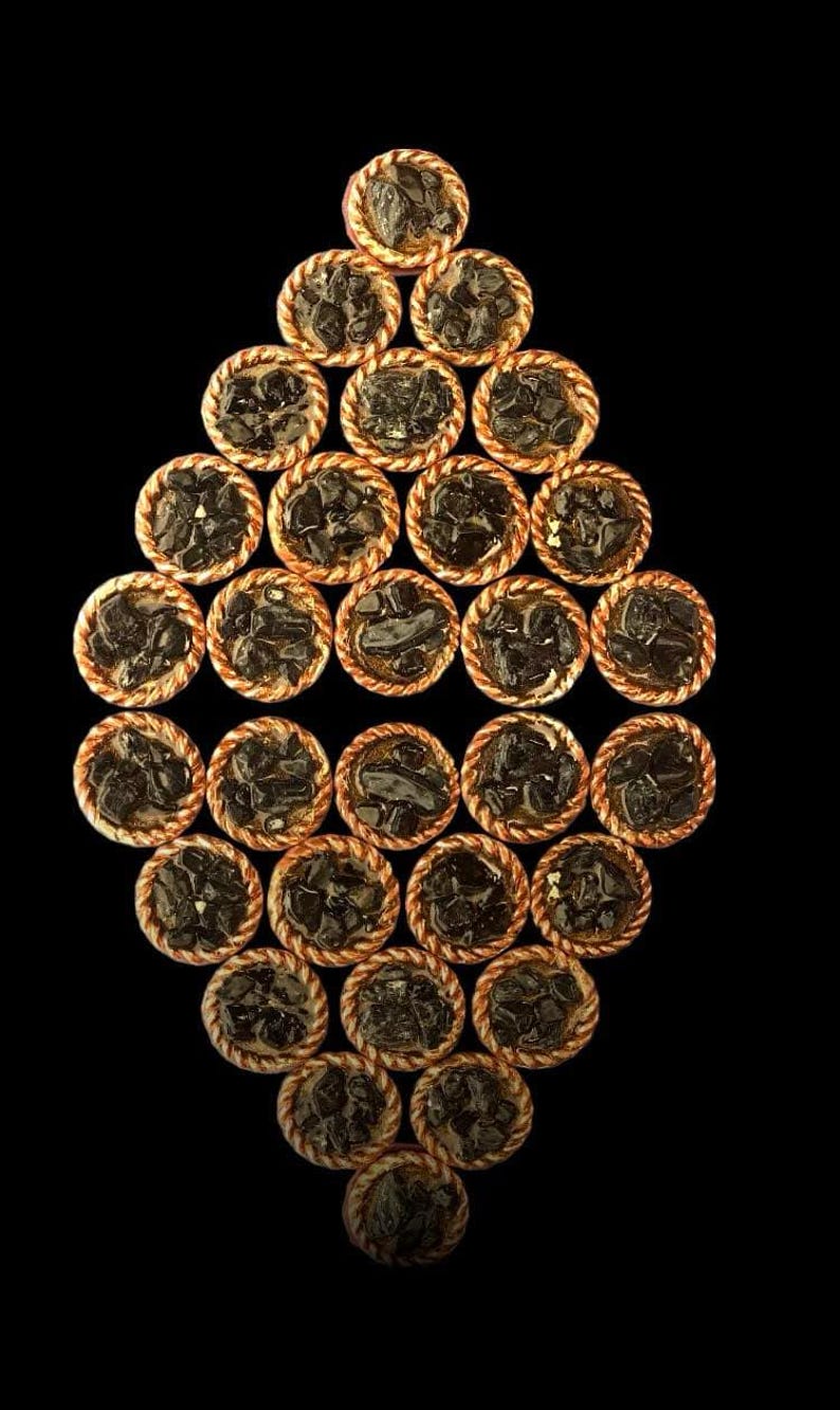 May include: A diamond-shaped arrangement of small, individual pies with a dark filling. The pies have a golden brown crust and are arranged in a symmetrical pattern.