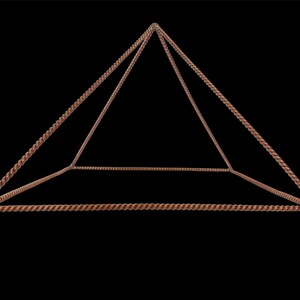 Op de afbeelding: Een koperkleurige piramidevormige structuur met een gedraaid touwontwerp. De geometrische sculptuur heeft een vierkante basis en vier driehoekige zijden, waardoor een driedimensionale vorm ontstaat. De piramide staat tegen een zwarte achtergrond.
