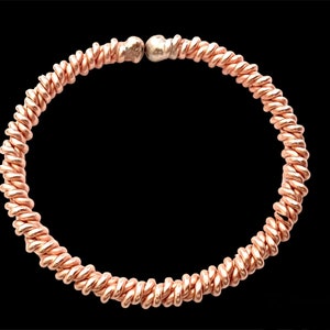 Op de afbeelding: Een roségouden gedraaide draad armband met een zilveren kraal accent.