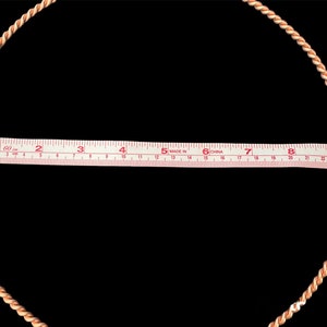 Puede incluir: Primer plano de un c&iacute;rculo de cuerda blanco y naranja con una cinta m&eacute;trica en el centro. La cinta indica "1 60 in 2 3 4 5 MADE IN CHINA 6 7 8 9 10".