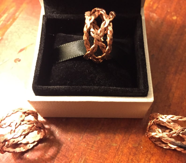 May include: Three rose gold braided rings in a white box. The rings are made of a woven metal design.