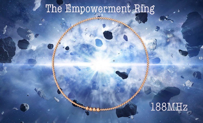 Puede incluir: Un anillo de color dorado con un dise&ntilde;o de cuerda y tres peque&ntilde;as cuentas. El anillo est&aacute; colocado sobre un fondo azul y blanco con una luz blanca brillante en el centro. El texto "The Empowerment Ring" est&aacute; en la parte superior de la imagen y "188MHz" en la parte inferior.