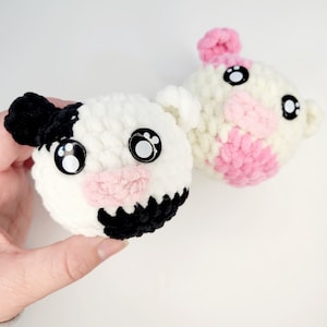 May include: Two crocheted stuffed animals with googly eyes. One is white with black spots and a pink nose, the other is white with pink accents.
