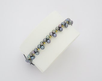 Bracelet élastique avec perles grises et petites perles en argent dorées.