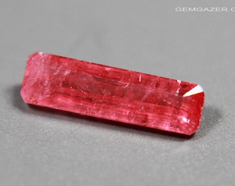 Puede incluir: Una piedra preciosa rectangular facetada de color rojo intenso con una superficie lisa y pulida.