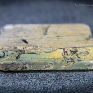 May include: A rectangular gemstone with rounded edges. The stone displays a mix of colours, including beige, green, yellow, and pink, with a textured surface. The gemstone is likely used for jewellery or decorative purposes.