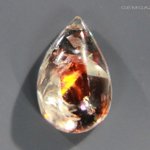 Pu&ograve; includere: Una pietra preziosa trasparente a forma di lacrima con inclusiones di rosso, arancione e giallo. La pietra preziosa &egrave; sfaccettata e ha un'alta lucidatura.