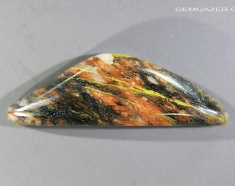 May include: A polished, triangular gemstone with a mix of colors. The stone features orange, black, yellow, and white hues, with a glossy finish. The gemstone is set against a gray background.