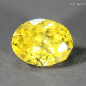 Puede incluir: Una gema ovalada de color amarillo brillante con facetas.