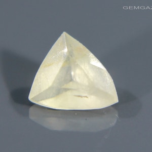 May include: A clear, triangular, faceted gemstone with a slight yellow hue.