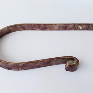 Può includere: Un fermatenda decorativo a forma di C curva. Il fermatenda è di colore bordeaux screziato con un bordo dorato metallico. Ha un'estremità piatta e rettangolare con due fori preforati per il montaggio.