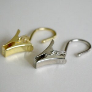 May include: Two curtain clips, one gold and one silver, with a hook on the end.