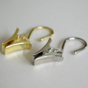 May include: Two curtain clips, one gold and one silver, with a hook on the end.