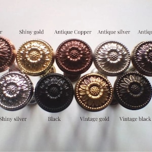 May include: Assortment of ten decorative metal knobs in various finishes, including copper, gold, silver, and black. Each knob features a raised sunflower design.