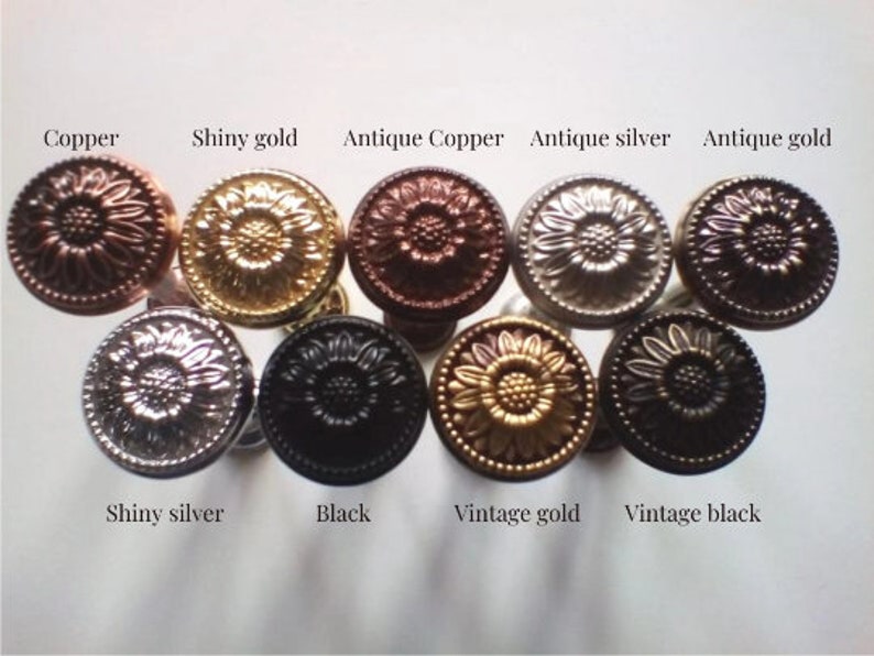 May include: Assortment of ten decorative metal knobs in various finishes, including copper, gold, silver, and black. Each knob features a raised sunflower design.