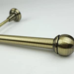 May include: A close-up of a brushed brass curtain pole with a round finial. The pole is attached to a wall bracket.