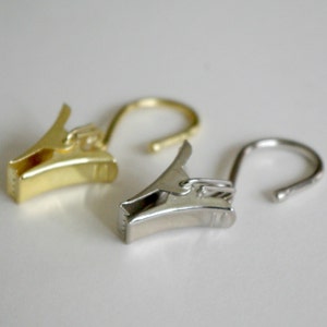 May include: Two curtain clips, one gold and one silver, with a hook on each end.