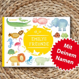 May include: A colorful children's book with the title "Emilys Freunde" and the text "Mit Deinem Namen" on a red starburst. The book features illustrations of animals including a flamingo, a turtle, a lion, an elephant, a rhinoceros, a seahorse, a raccoon, a crocodile, a frog, a ladybug, an octopus, and a pig.