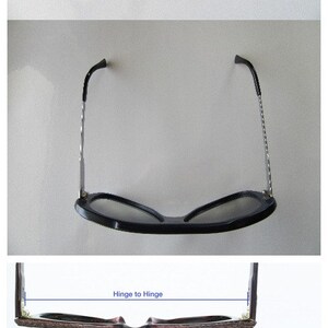 K&ouml;nnte beinhalten: Eine Brille mit braunem Holzrahmen und schwarzen Gl&auml;sern. Die Brille hat einen Scharnier-zu-Scharnier-Abstand von 13 cm, einen B&uuml;gel-zu-B&uuml;gel-Abstand von 14 cm, eine Linsenbreite von 5 cm, einen Stegbreite von 2 cm, eine B&uuml;gell&auml;nge von 14,5 cm und eine Gesamtgestellh&ouml;he von 4,5 cm.