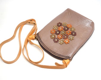 May include: A brown leather crossbody bag with a floral design. The flowers are made of leather and are in shades of brown, orange, and yellow.