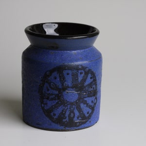 Puede incluir: Un jarrón de cerámica azul con un borde negro y un diseño geométrico negro.