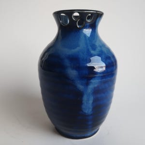 以下が含まれることがあります： 手描きでユニークなデザインが施された青い陶器の花瓶。花瓶は口が広く、首が細く、青と白の渦巻き模様で飾られています。