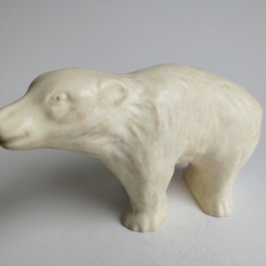 Könnte beinhalten: Eine weiße Keramikfigur eines Eisbären. Der Bär steht auf allen Vieren und hat ein realistisches Aussehen.