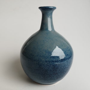 May include: A small, round, blue ceramic vase with a narrow neck.