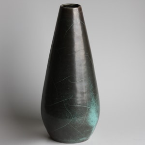 May include: A tall, dark green ceramic vase with a crackled glaze and a teal blue pattern. The vase has a narrow neck and a wide base.
