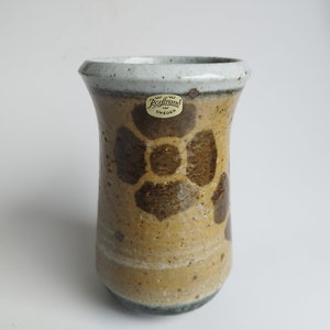 May include: A brown and white ceramic vase with a floral design. The vase has a label that reads "Rörstrand Sweden".