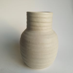 May include: A white ceramic vase with a rounded body and a textured, ridged surface.