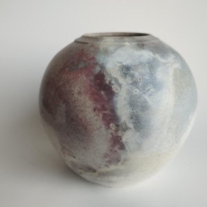 May include: A round ceramic vase with a mottled glaze in shades of grey, white, and purple.