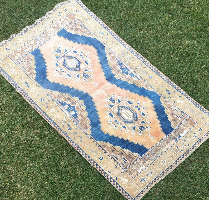 May include: A vintage rug with a blue and beige pattern. The rug has a faded, distressed look and features intricate geometric designs.