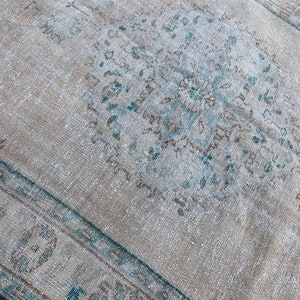 May include: A vintage rug with a faded blue and brown pattern. The rug has a distressed look and is made of a soft, natural fiber.