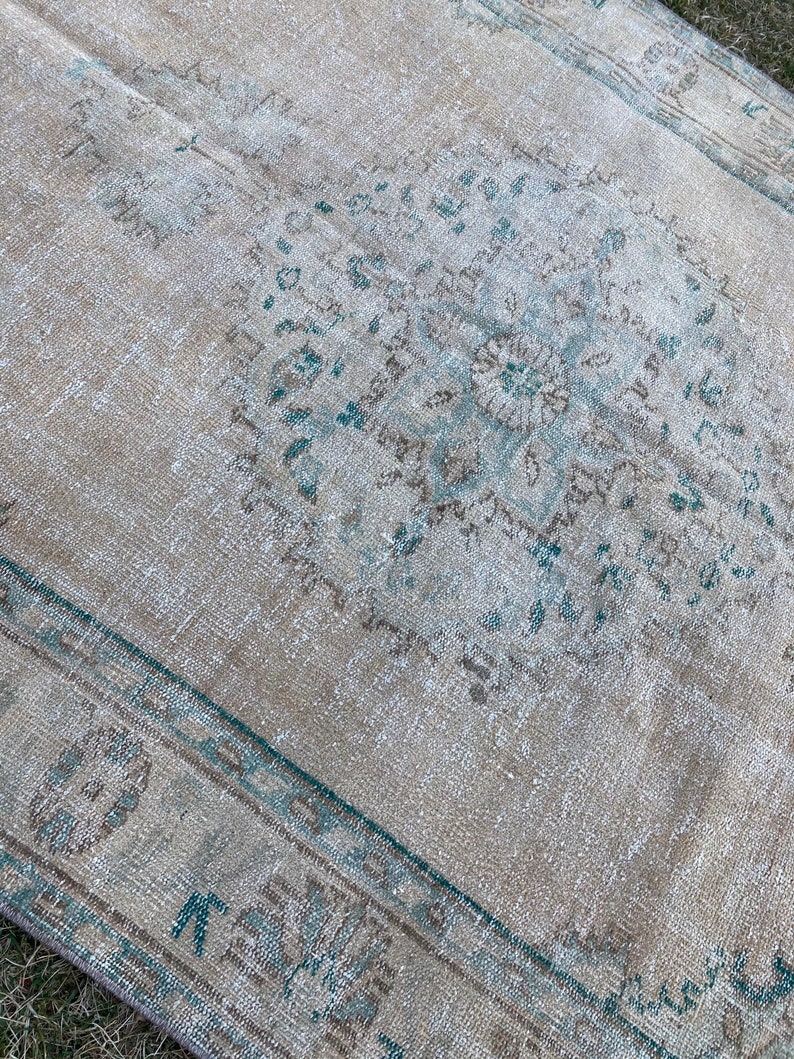 May include: A vintage rug with a faded blue and brown pattern. The rug has a distressed look and is made of a soft, natural fiber.