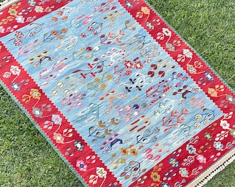 May include: A blue and red patterned rug with a fringe border. The rug features a floral design with intricate details.