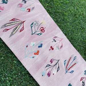 May include: A pink runner rug with a floral pattern. The rug features a variety of colorful flowers and leaves in shades of red, blue, green, and yellow.