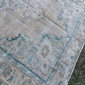 May include: A vintage rug with a faded light blue and brown pattern. The rug has a distressed look and is made of a soft, woven material.