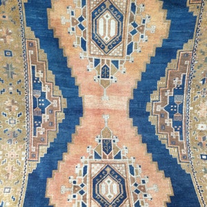 May include: A vintage rug with a blue and orange geometric pattern. The rug has a central medallion with a repeating design of diamonds and squares.