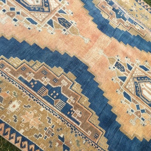 May include: A vintage rug with a blue and beige geometric pattern. The rug has a faded, distressed look, giving it a unique and rustic charm.
