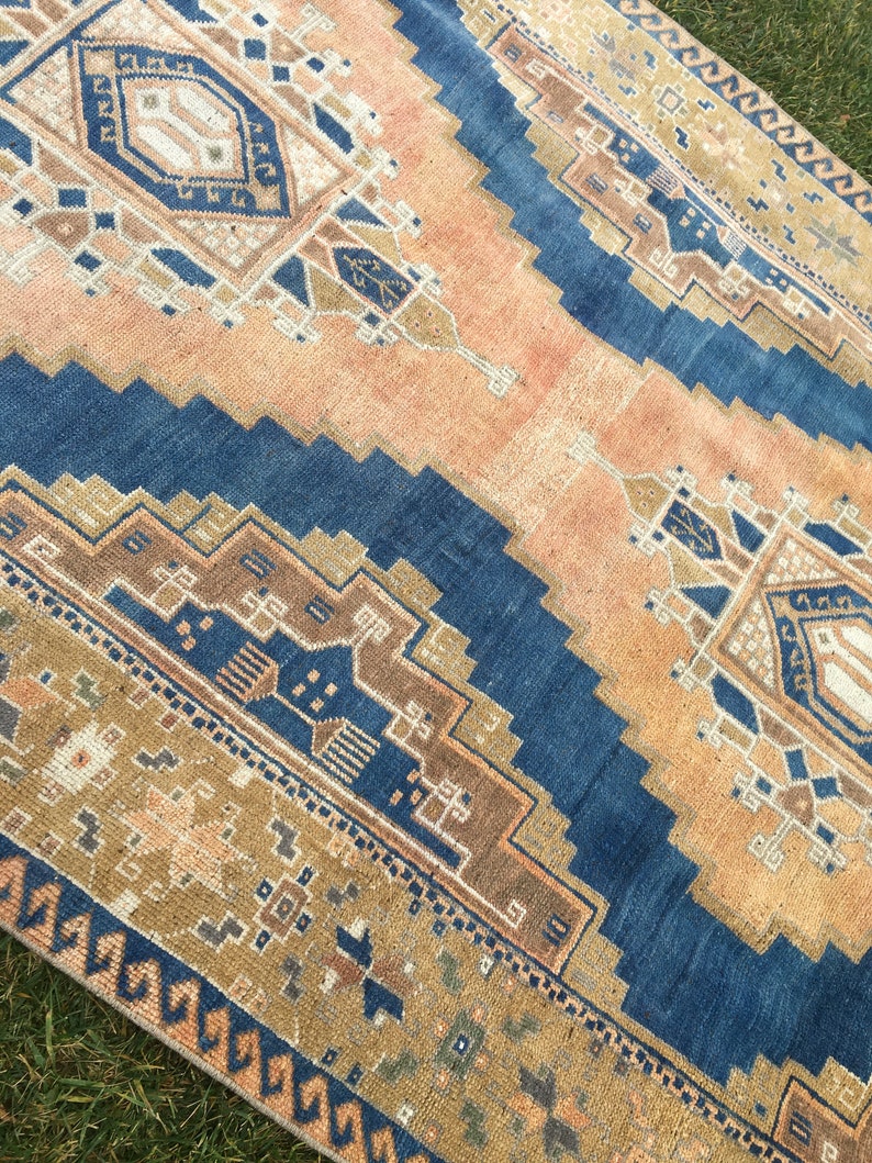 May include: A vintage rug with a blue and beige geometric pattern. The rug has a faded, distressed look, giving it a unique and rustic charm.