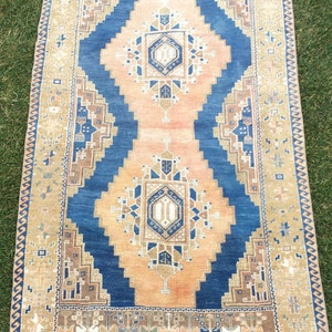May include: A vintage rug with a blue and beige colour scheme. The rug has a geometric pattern with a central medallion. The rug is in good condition and has a worn look.