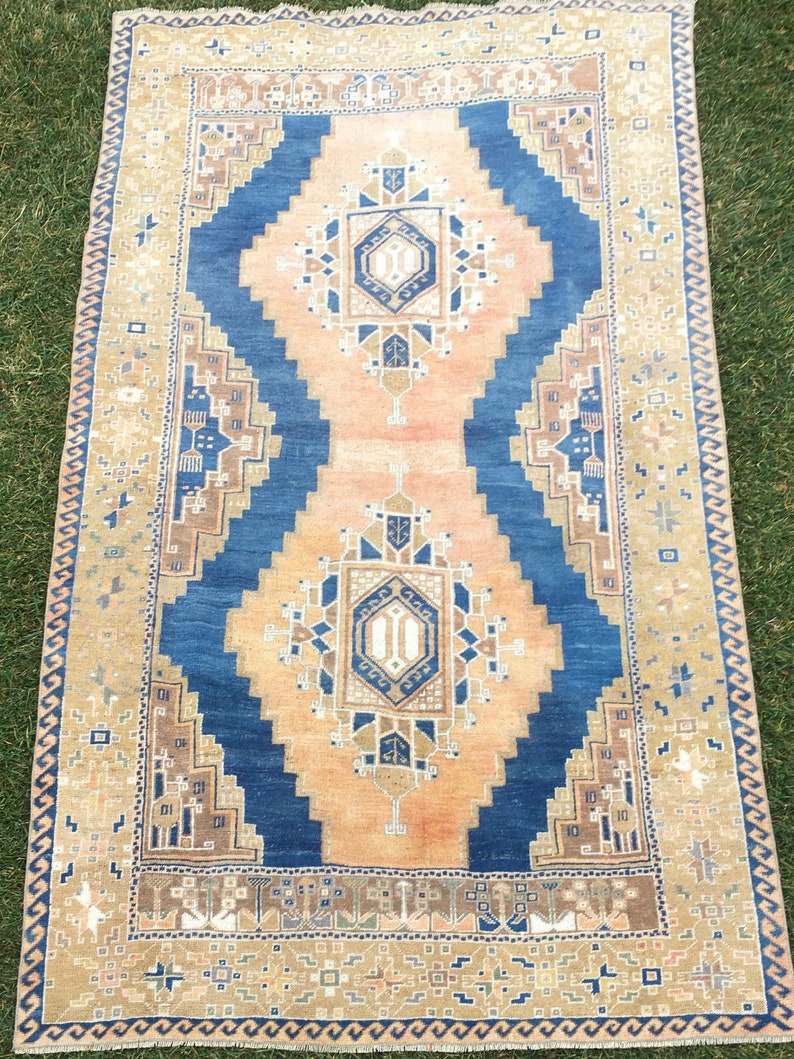 May include: A vintage rug with a blue and beige colour scheme. The rug has a geometric pattern with a central medallion. The rug is in good condition and has a worn look.
