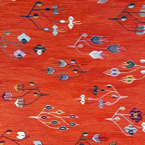 Pu&ograve; includere: Un tessuto rosso con un motivo floreale stilizzato ripetuto in tonalit&agrave; di blu, bianco, viola e oro.